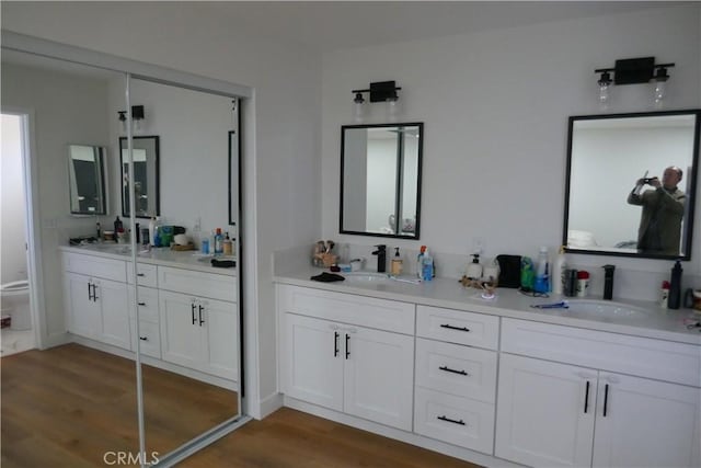full bath featuring wood finished floors, double vanity, and toilet