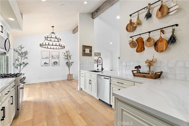249 Calle Empalme, San Clemente, CA 92672 - kitchen with appliances with stainless steel finishes, a sink, light stone counters, backsplash, and light wood-style floors
