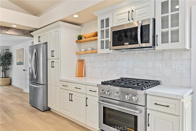 249 Calle Empalme, San Clemente, CA 92672 - kitchen with appliances with stainless steel finishes, light wood finished floors, glass insert cabinets, white cabinetry, and backsplash