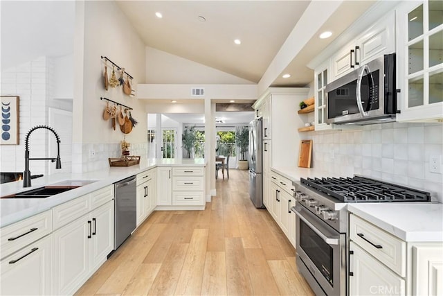 249 Calle Empalme, San Clemente, CA 92672 - kitchen with stainless steel appliances, a sink, vaulted ceiling, a peninsula, and light wood-style floors