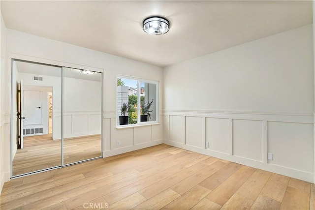 249 Calle Empalme, San Clemente, CA 92672 - unfurnished bedroom with light wood-style floors, a decorative wall, a closet, and wainscoting