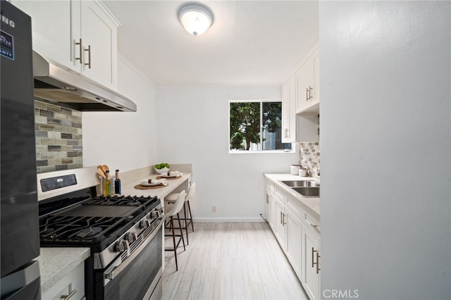 617 Cedar Ave Unit 11, Long Beach, CA 90802 - kitchen featuring stainless steel gas range, under cabinet range hood, a sink, tasteful backsplash, and light countertops