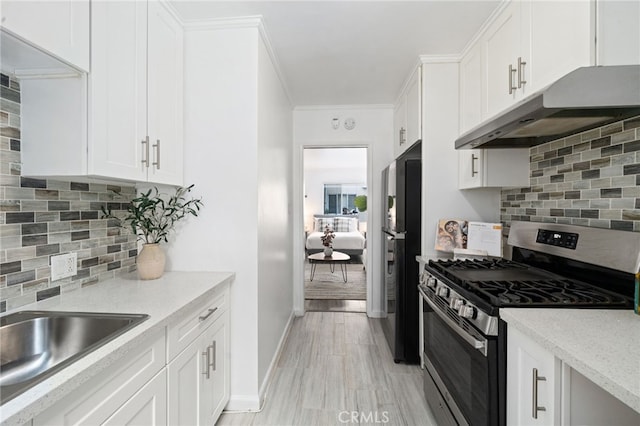 617 Cedar Ave Unit 11, Long Beach, CA 90802 - kitchen with stainless steel range with gas cooktop, under cabinet range hood, freestanding refrigerator, white cabinetry, and backsplash