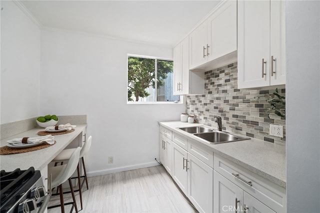 617 Cedar Ave Unit 11, Long Beach, CA 90802 - kitchen with a sink, decorative backsplash, ornamental molding, light countertops, and white cabinetry
