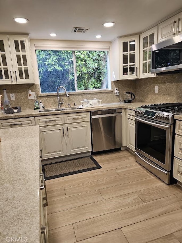 9315 Woodman Ave Unit 8, Arleta, CA 91331 - kitchen featuring appliances with stainless steel finishes, a sink, white cabinets, backsplash, and recessed lighting