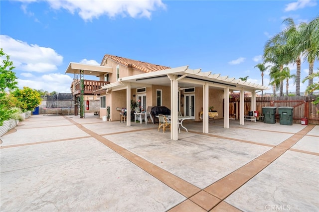 11149 Liverpool Ln, Riverside, CA 92503 - rear view of house featuring a trampoline, a patio area, fence, stucco siding, and a tiled roof