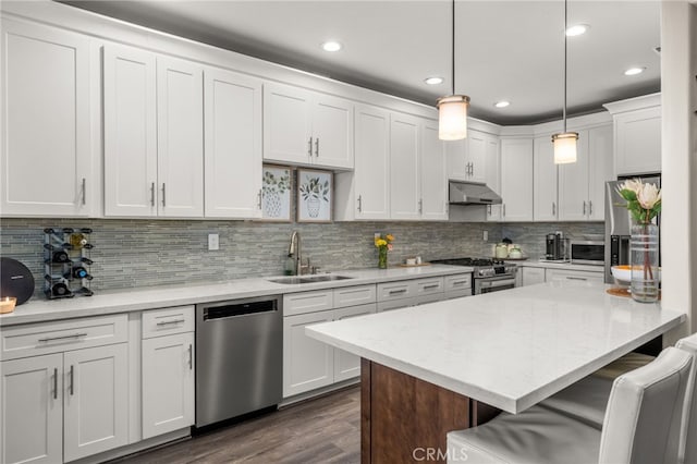 2130 Almeria St Unit 101, Corona, CA 92879 - kitchen with appliances with stainless steel finishes, a sink, under cabinet range hood, a breakfast bar, and white cabinets