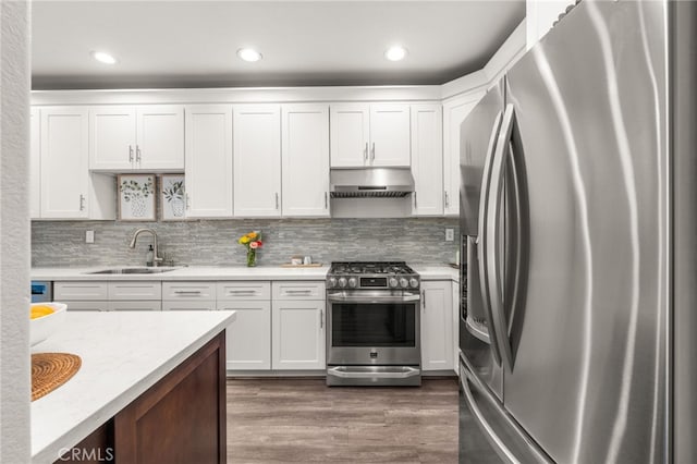 2130 Almeria St Unit 101, Corona, CA 92879 - kitchen with appliances with stainless steel finishes, a sink, under cabinet range hood, white cabinetry, and wood finished floors