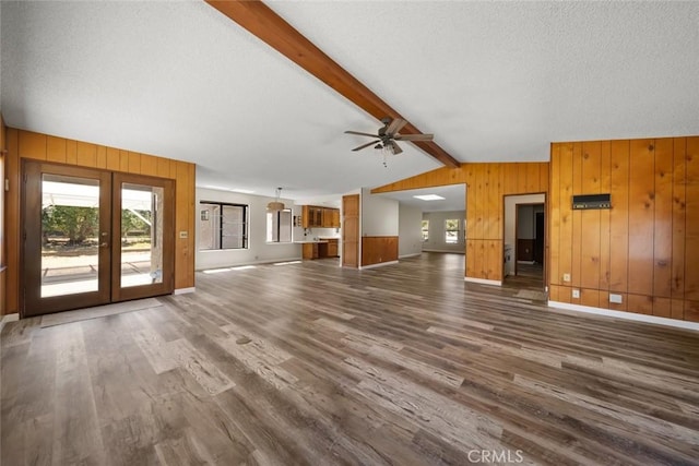 410 N Las Flores Dr, Nipomo, CA 93444 - unfurnished living room featuring dark wood-style floors, wooden walls, healthy amount of natural light, french doors, and a textured ceiling