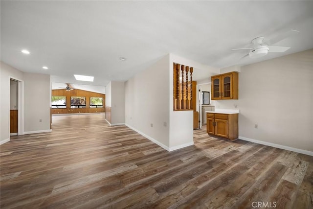 410 N Las Flores Dr, Nipomo, CA 93444 - unfurnished living room featuring a ceiling fan, wood finished floors, a skylight, baseboards, and vaulted ceiling