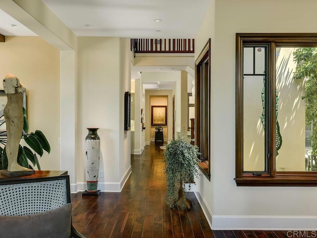 corridor featuring dark wood-style flooring and baseboards
