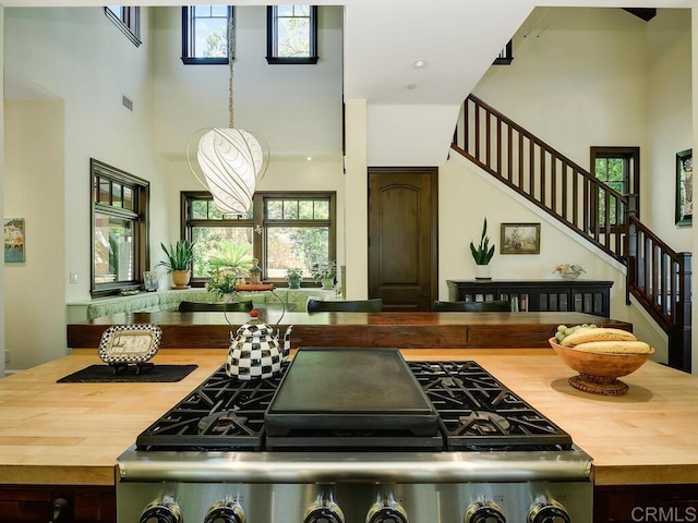 kitchen featuring butcher block countertops, stove, a high ceiling, and healthy amount of natural light