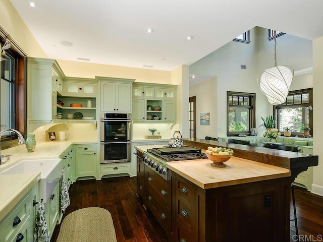 kitchen featuring open shelves, green cabinets, appliances with stainless steel finishes, recessed lighting, and a towering ceiling