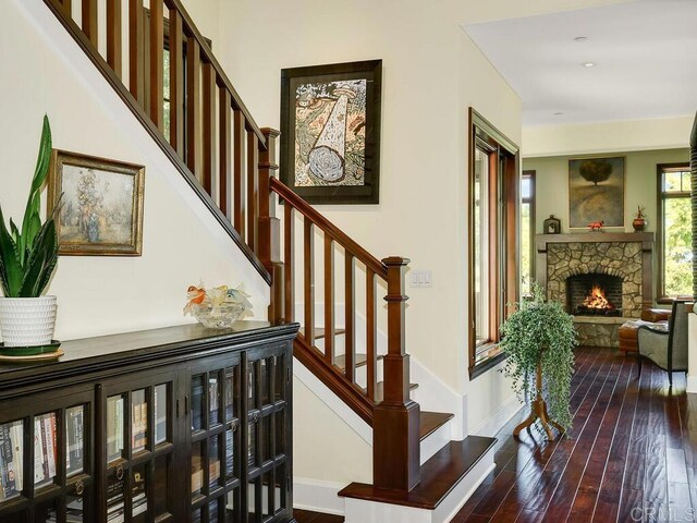 staircase featuring wood-type flooring, a fireplace, and baseboards