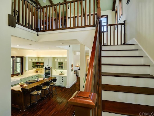 stairway featuring hardwood / wood-style flooring and a towering ceiling