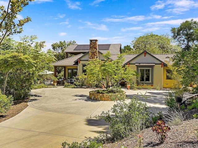 view of front of home with solar panels and a chimney