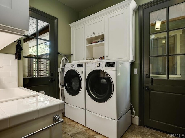 washroom with washing machine and dryer, cabinet space, and stone finish flooring