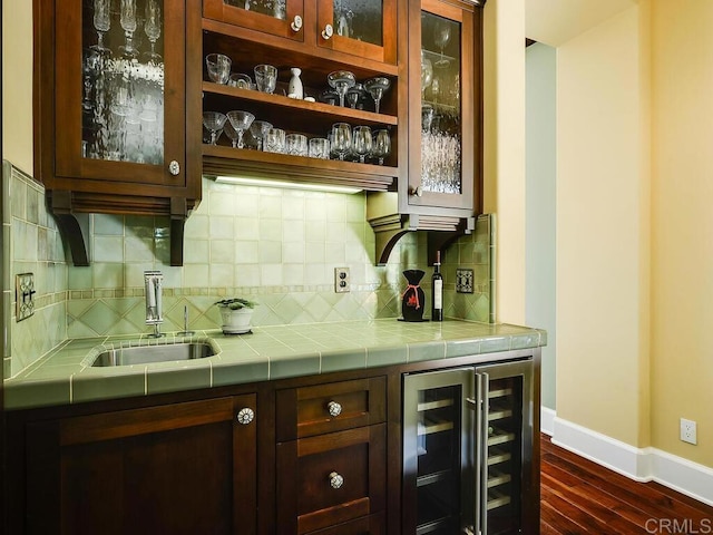 indoor wet bar featuring wine cooler, baseboards, backsplash, and dark wood-type flooring