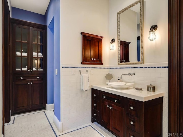 bathroom featuring tile walls, vanity, tile patterned flooring, and a wainscoted wall