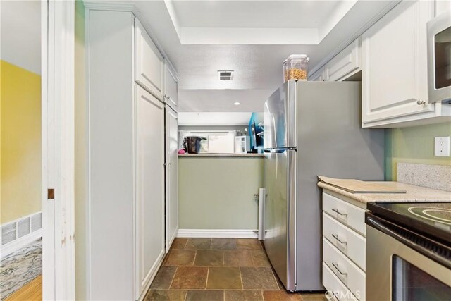 6621 Caro St Unit 111, Paramount, CA 90723 - kitchen with stainless steel appliances, white cabinetry, light countertops, a tray ceiling, and baseboards