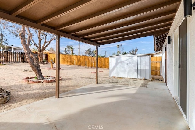 view of patio / terrace with a storage unit, a fenced backyard, and an outbuilding