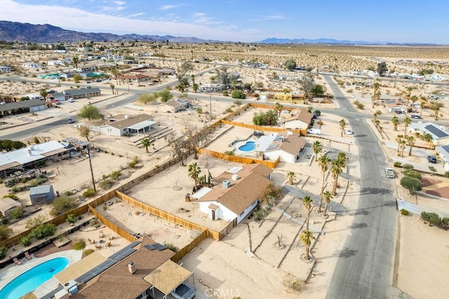 aerial perspective of suburban area with a pool, a mountain backdrop, and a desert landscape