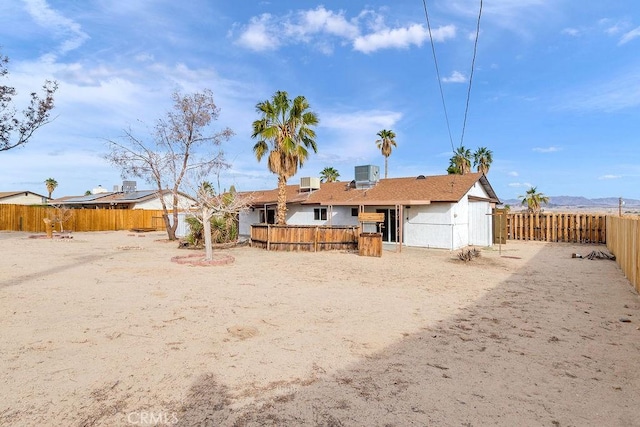 rear view of property with a fenced backyard and central AC unit
