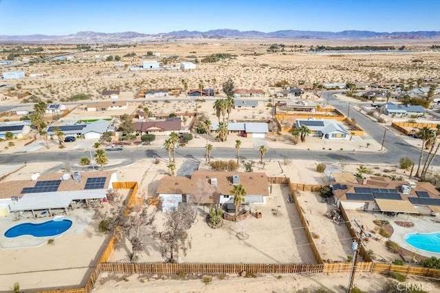 aerial view of residential area with a pool area, a mountainous background, and a desert landscape