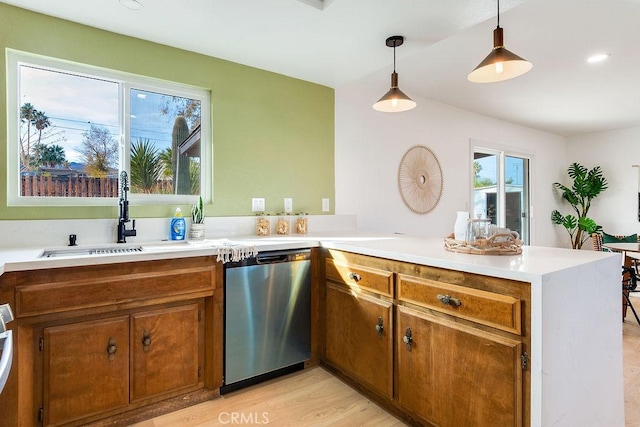 kitchen with stainless steel dishwasher, a peninsula, a sink, brown cabinets, and recessed lighting