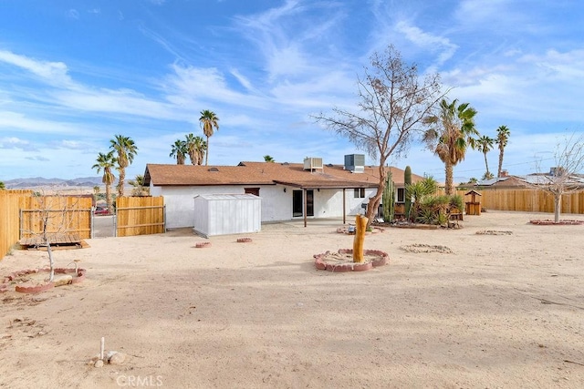 back of house featuring fence, stucco siding, and central air condition unit