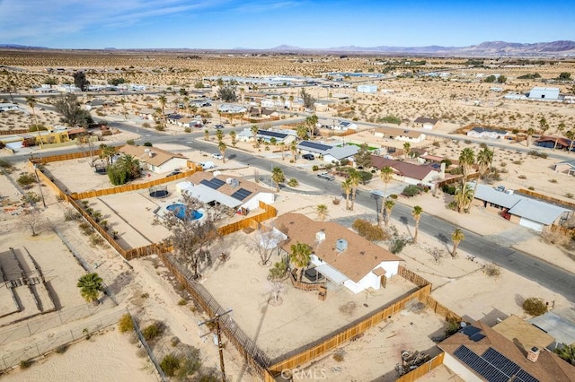 aerial view of sparsely populated area featuring a desert landscape, a mountain backdrop, and nearby suburban area