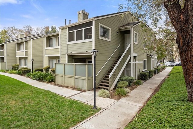 5814 Old Village Rd Unit 216, Yorba Linda, CA 92887 - rear view of property featuring stairway, a lawn, and a chimney