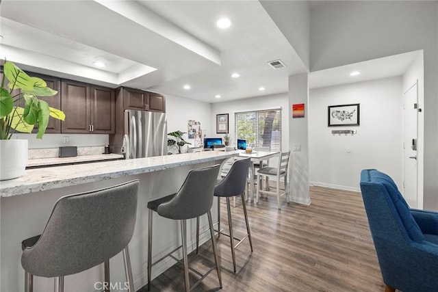 5814 Old Village Rd Unit 216, Yorba Linda, CA 92887 - kitchen with freestanding refrigerator, baseboards, dark brown cabinets, a kitchen bar, and wood finished floors