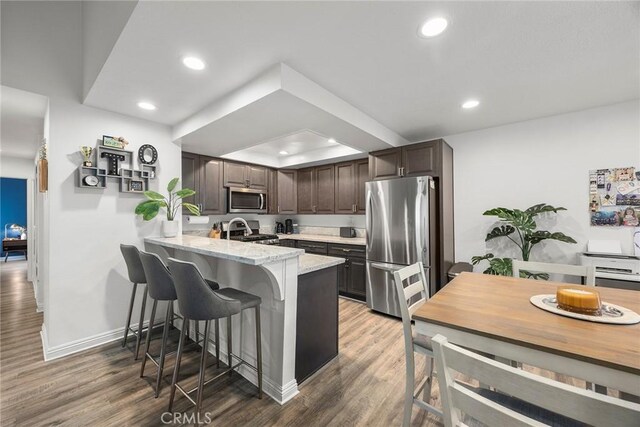 5814 Old Village Rd Unit 216, Yorba Linda, CA 92887 - kitchen featuring stainless steel appliances, a peninsula, a kitchen bar, recessed lighting, and wood finished floors
