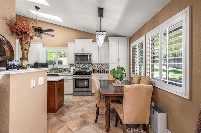 35189 Ravencrest Ct, Yucaipa, CA 92399 - kitchen with appliances with stainless steel finishes, tasteful backsplash, vaulted ceiling, white cabinetry, and light countertops