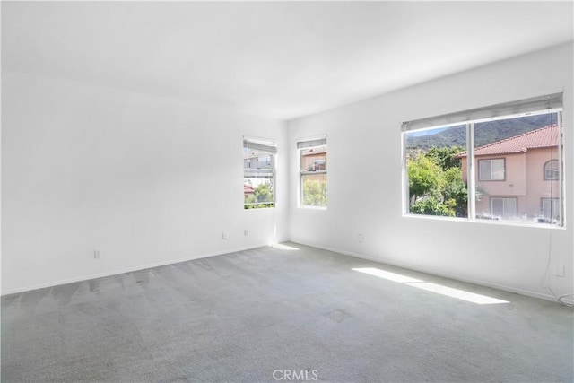 empty room featuring carpet floors, healthy amount of natural light, and baseboards