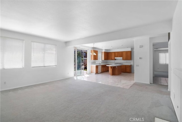 unfurnished living room with light colored carpet, plenty of natural light, and baseboards