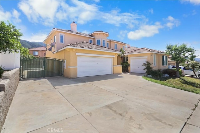 mediterranean / spanish home with stucco siding, a chimney, concrete driveway, an attached garage, and a tiled roof