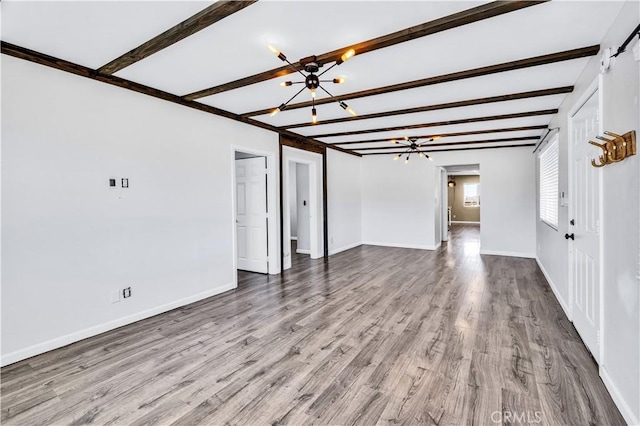 57330 Old Haggard Rd, Yucca Valley, CA 92284 - unfurnished living room featuring a chandelier, beamed ceiling, wood finished floors, and baseboards