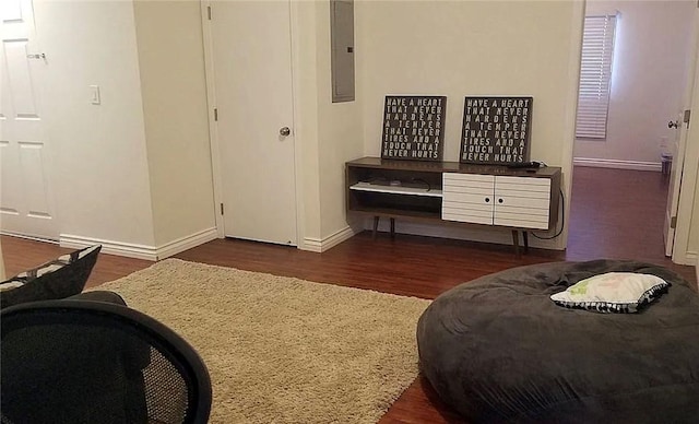 bedroom featuring wood finished floors, baseboards, and electric panel