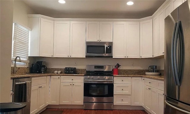 kitchen with stainless steel appliances, white cabinets, recessed lighting, dark wood-type flooring, and dark stone counters