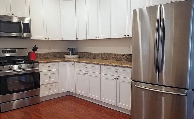 kitchen with stainless steel appliances, white cabinetry, dark wood-style flooring, and light stone countertops