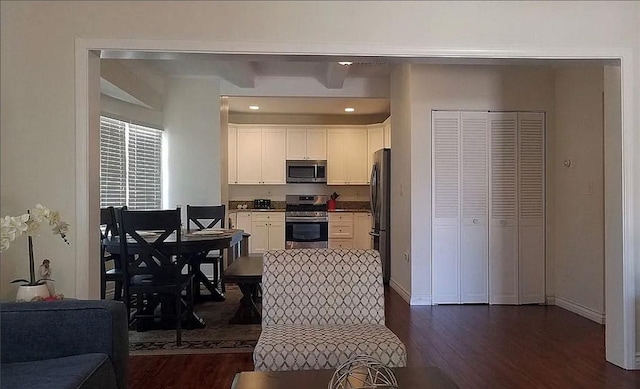 kitchen featuring range, stainless steel microwave, dark wood finished floors, white cabinets, and baseboards