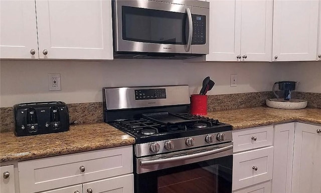 kitchen featuring stainless steel appliances, white cabinetry, and light stone countertops