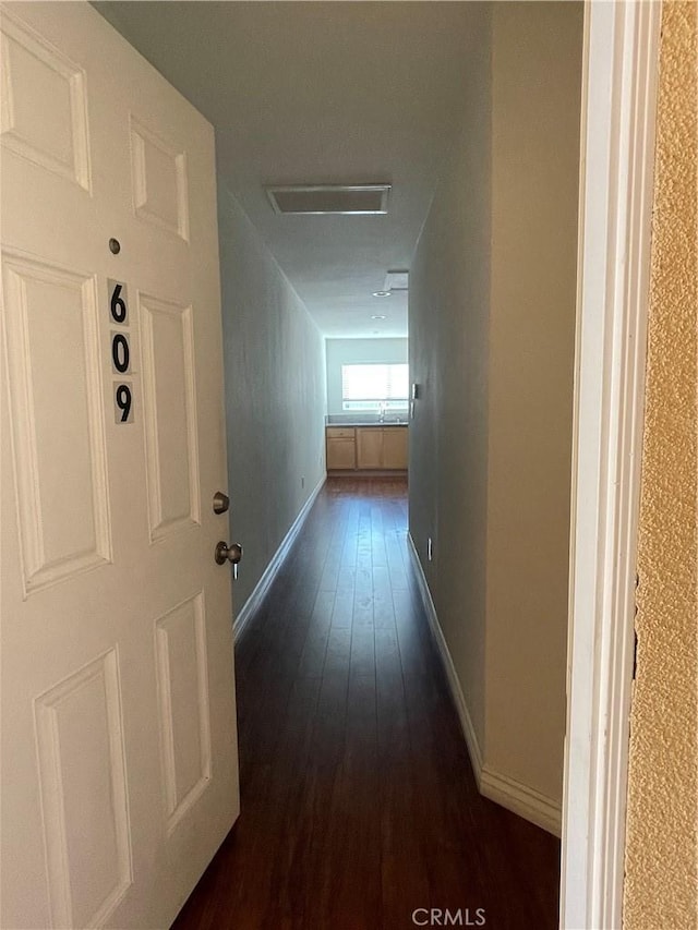 hallway featuring dark wood-style floors and baseboards