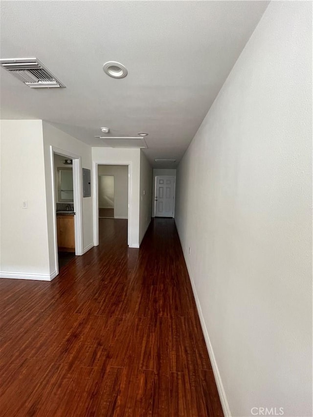 hallway with baseboards, wood finished floors, electric panel, and attic access