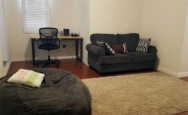 living room featuring wood finished floors, baseboards, and a desk
