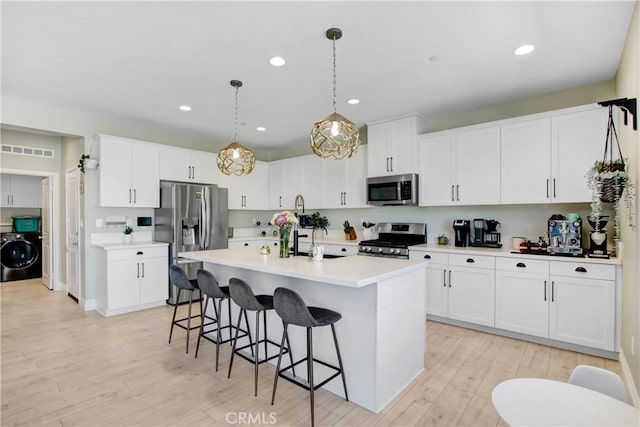 1212 Venice Ave, Mentone, CA 92359 - kitchen featuring appliances with stainless steel finishes, washer / dryer, a kitchen bar, light wood finished floors, and light countertops
