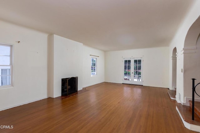 2577 Boulder Rd, Altadena, CA 91001 - unfurnished living room featuring wood finished floors, french doors, arched walkways, a fireplace with flush hearth, and baseboards