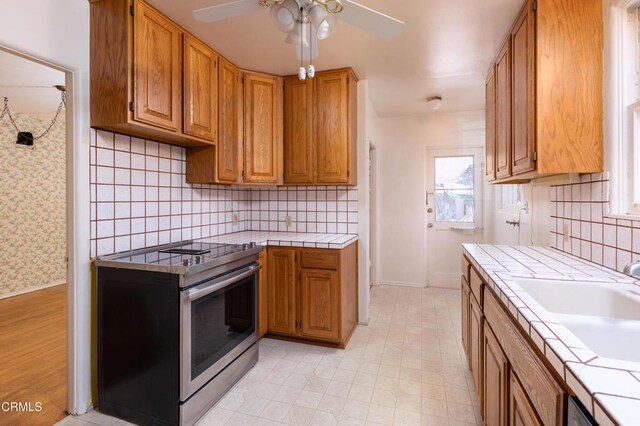 2577 Boulder Rd, Altadena, CA 91001 - kitchen featuring electric range, tile counters, a ceiling fan, decorative backsplash, and brown cabinetry